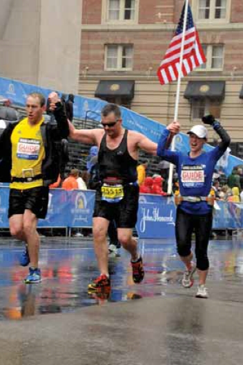 Gaston Bedard (centre) with running guides, Christopher Yule (left) and Melany Gauvin (right) at finish line of 2015 Boston Marathon. Credit: Marc Bedard
